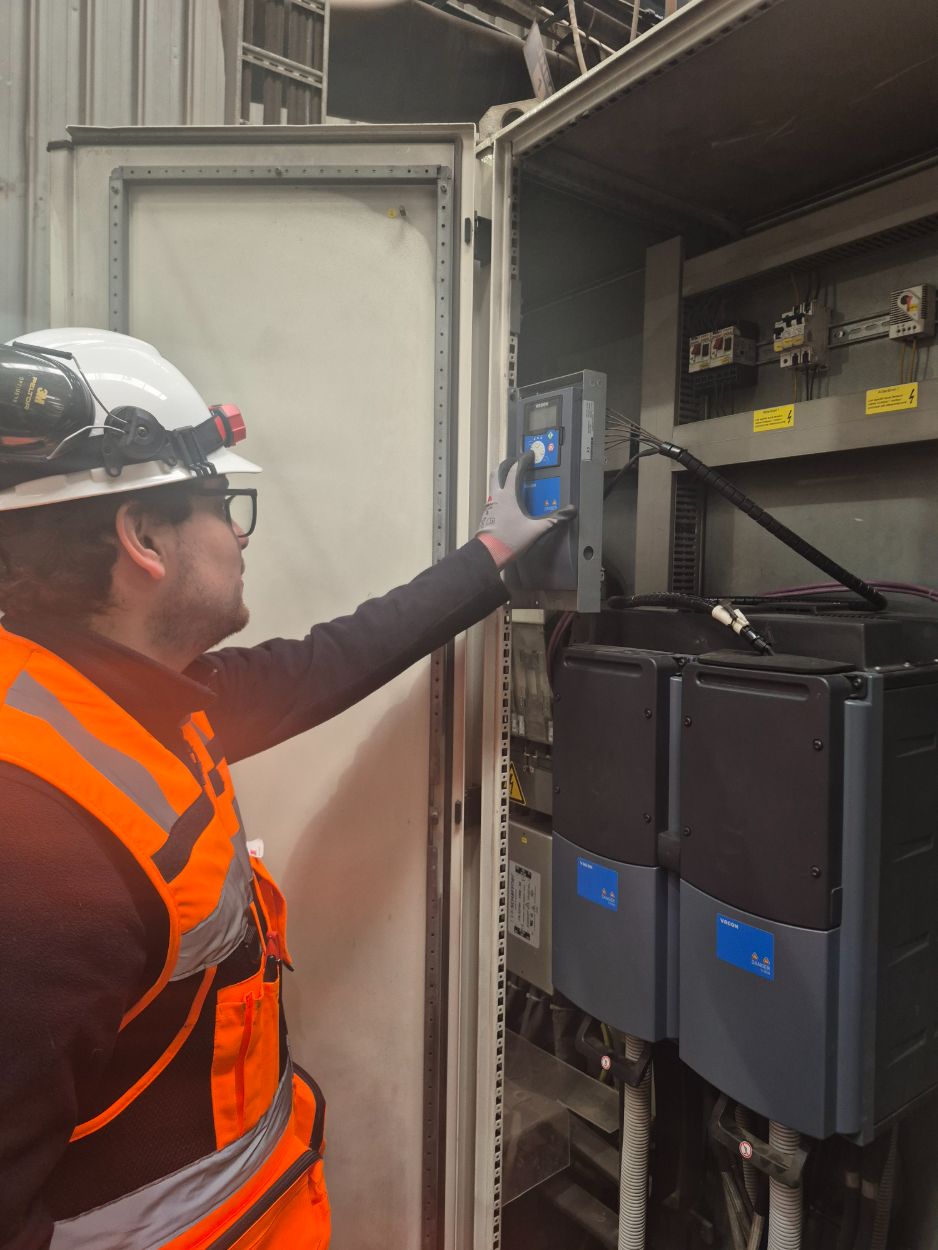 Técnico operando el panel de un variador de frecuencia instalado en un gabinete de planta